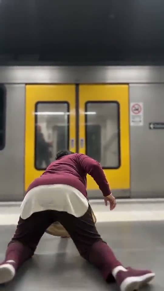 A woman sinks to her knees in front of the closed yellow train doors